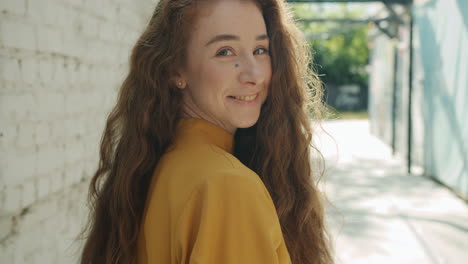 woman with long curly hair in a yellow shirt