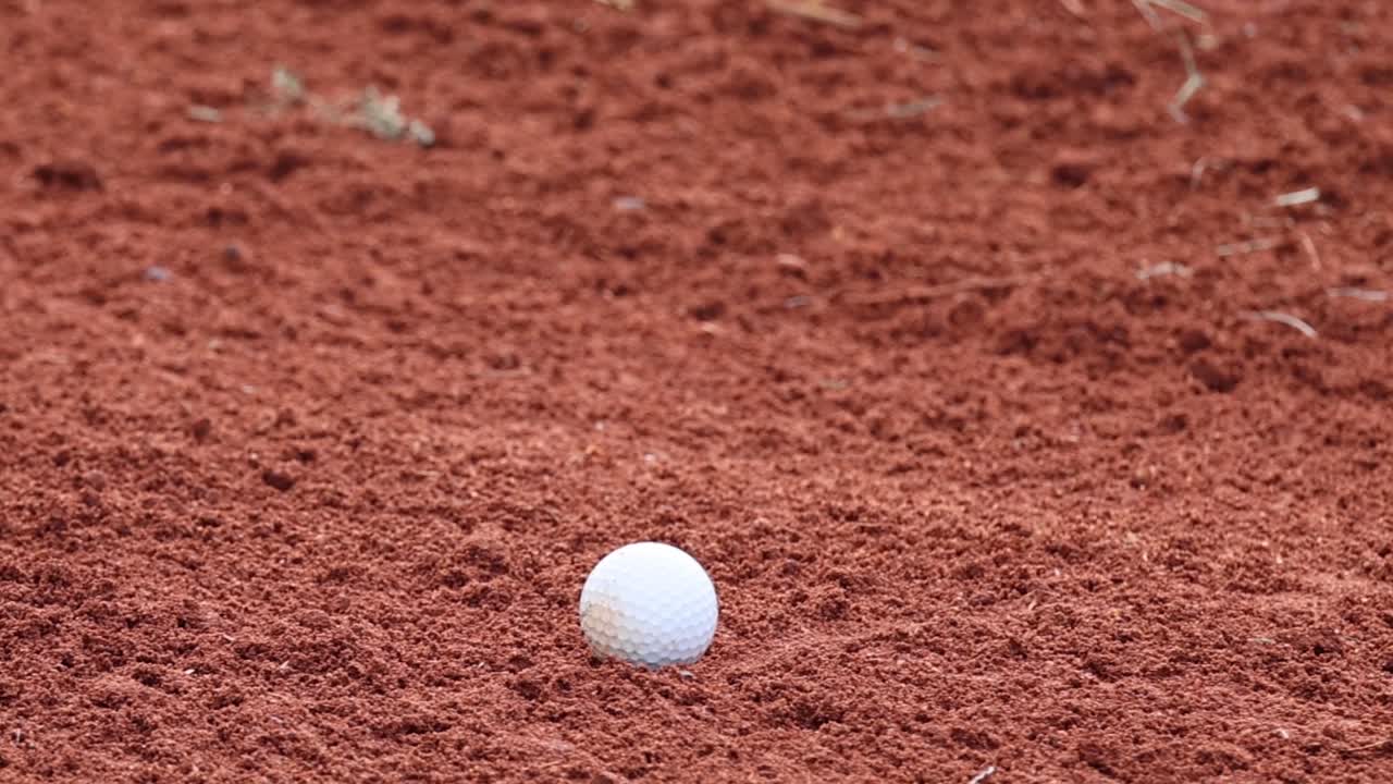 Sequenza ravvicinata di una mazza da golf che colpisce una palla in un bunker di sabbia, catturando l'esplosione di sabbia