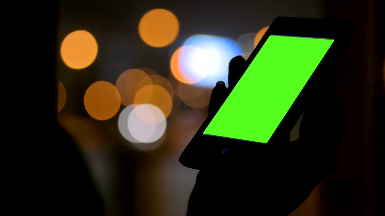 Woman looking at smartphone with green screen