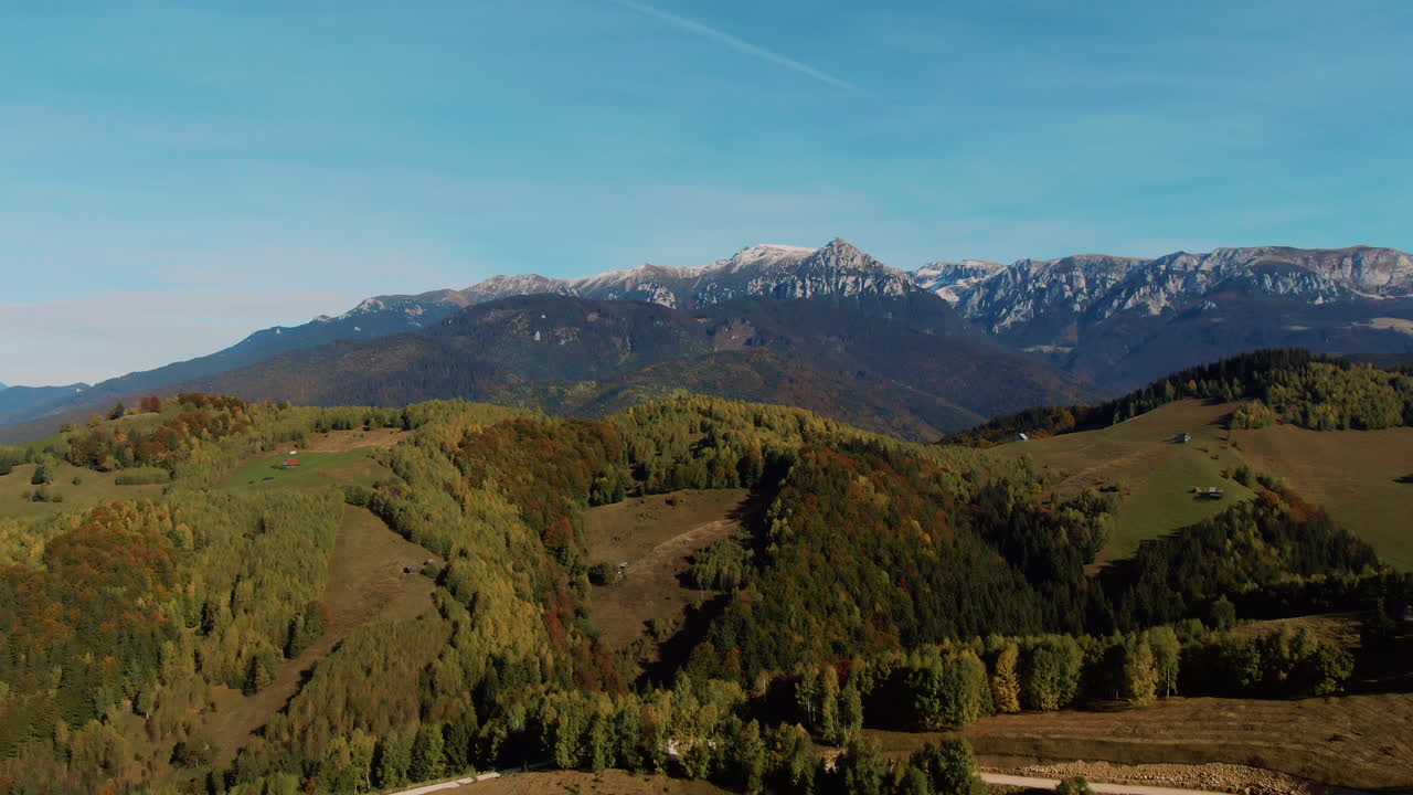 Splendida vista aerea con colline, valli e una cresta montuosa innevata in una giornata limpida e soleggiata