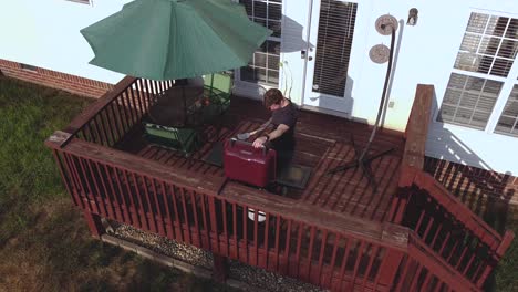 man grilling on a red deck, high angle