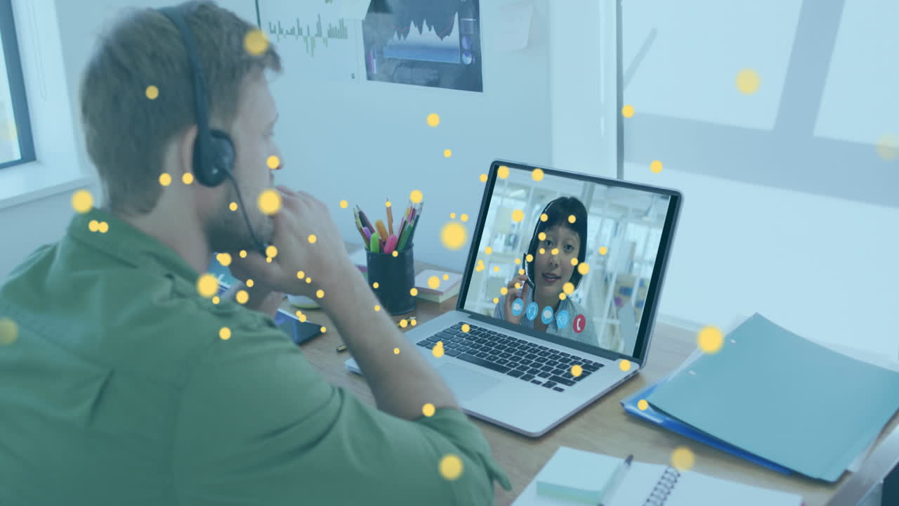 Animation of bitcoin icons over caucasian man using phone headset and laptop