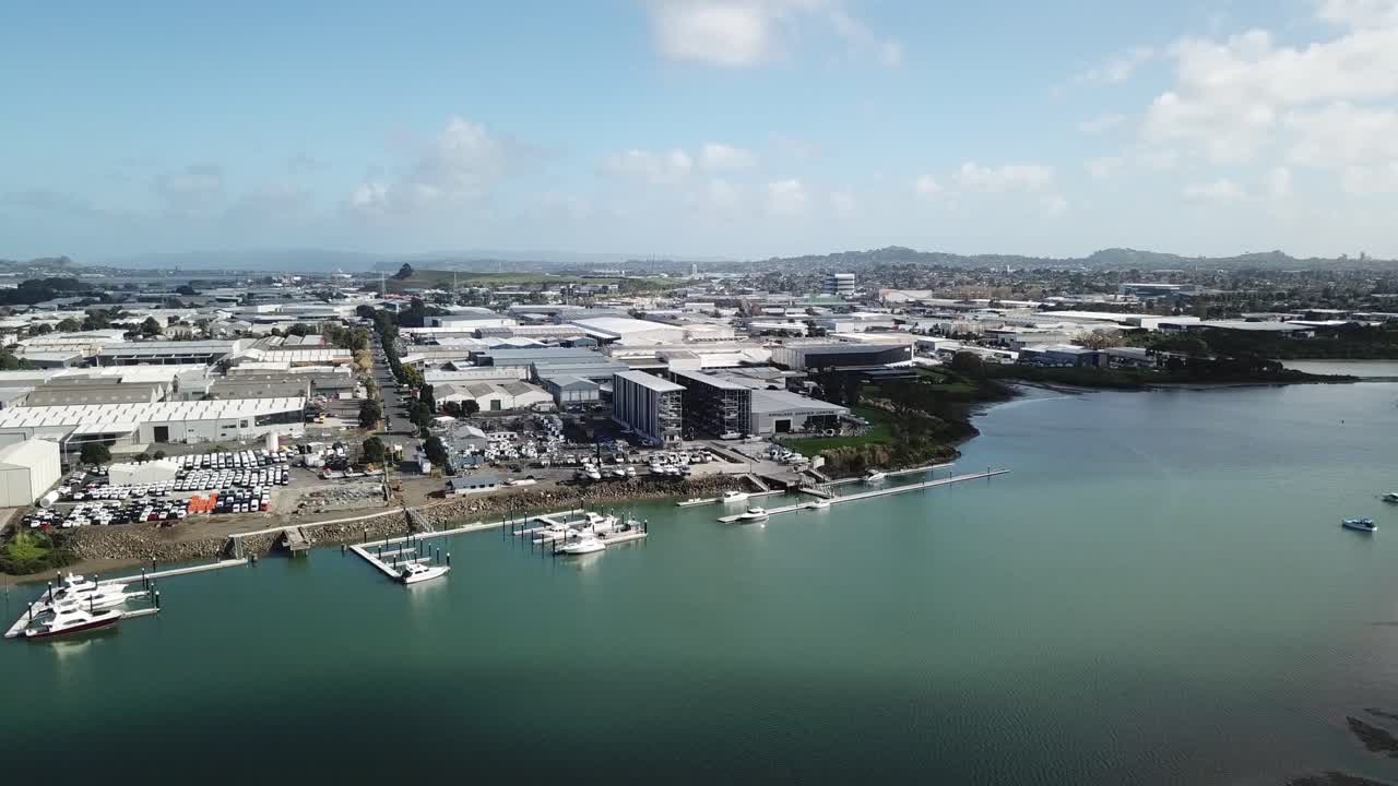 panorámica aérea 4k, toma de establecimiento de una fábrica de barcos junto a una marina con el fondo de las zonas industriales de los suburbios de auckland