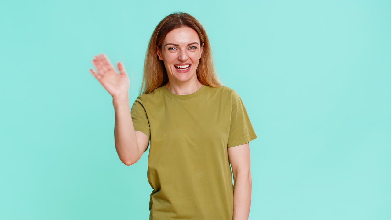 Woman waving hand and smiling joyfully saying hello greeting or welcoming with warm friendly gesture