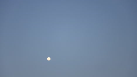 a time lapse close up of a full bright moon moving across the black dark night sky.