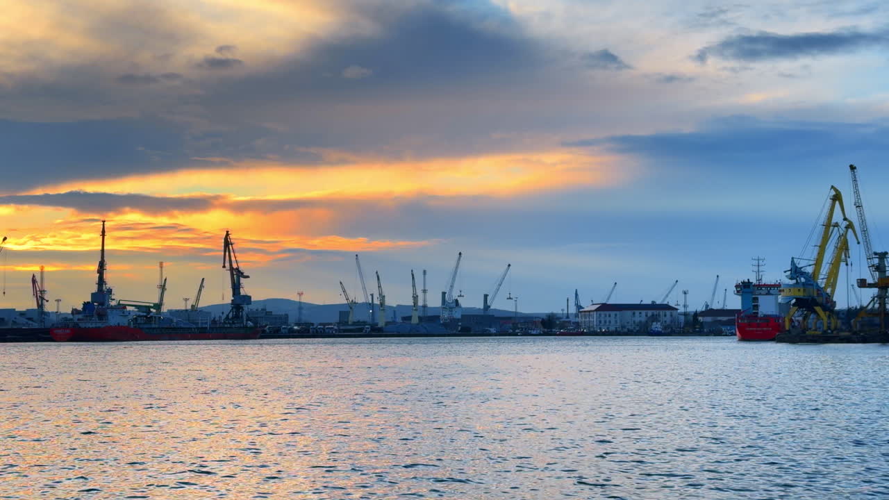 Burgas, Bulgaria, 29 October 2025: Sunset over the harbor with cranes and ships in the distance. Cranes and ships are seen in the harbor as the sun sets in the background