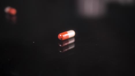 pills falling down on a black glass surface, mirror surface with a reflection on black background