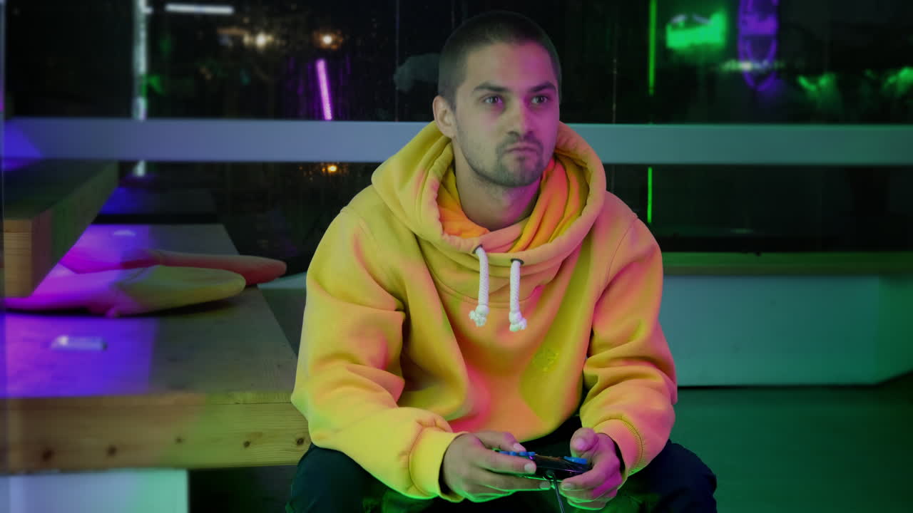Giovane uomo che gioca ai videogiochi in una stanza colorata