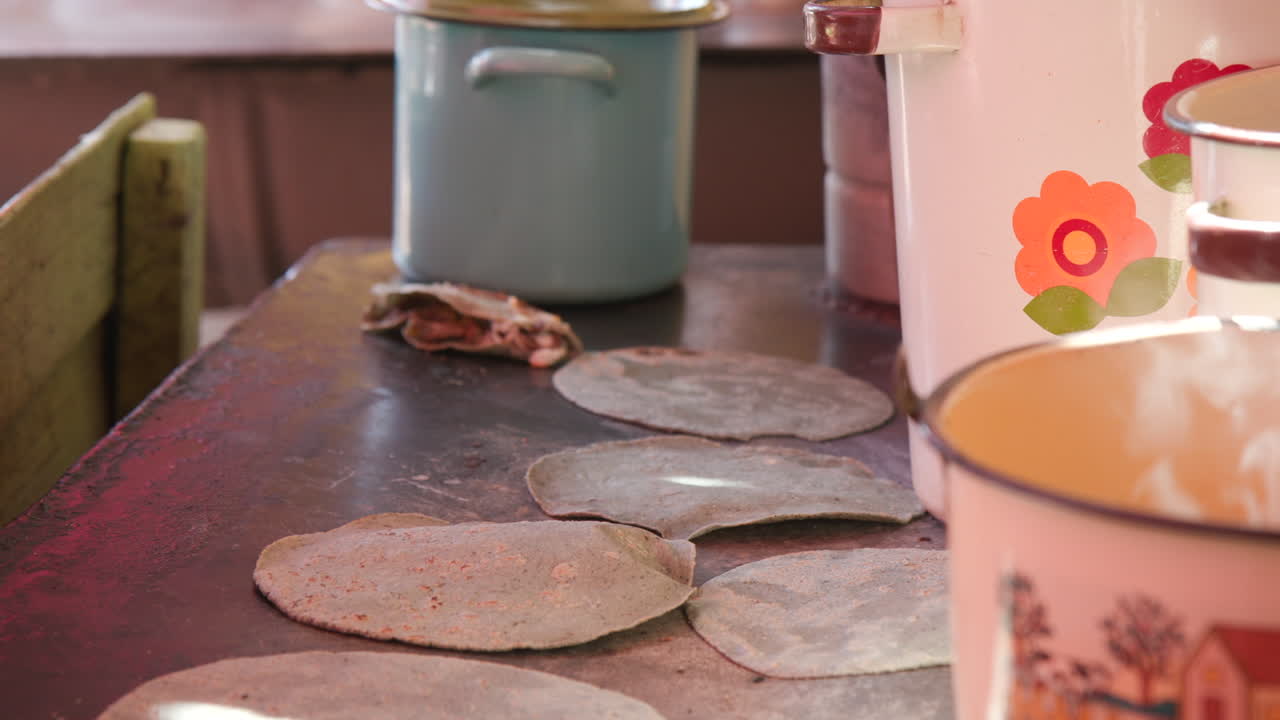Close up of a woman's hands as she cooks fresh corn tortillas on a hot plate of an outdoor kitchen in Mexico