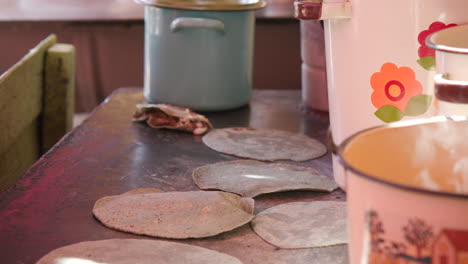 Close-up-of-a-woman's-hands-as-she-cooks-fresh-corn-tortillas-on-a-hot-plate-of-an-outdoor-kitchen-in-Mexico