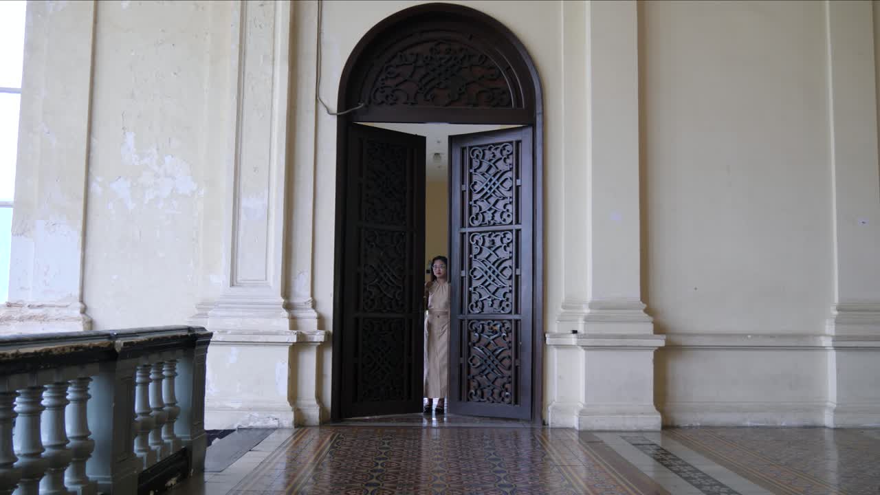 puerta de madera ornamentada en el histórico palacio gia long, ciudad de ho chi minh, vietnam con mujeres entrando