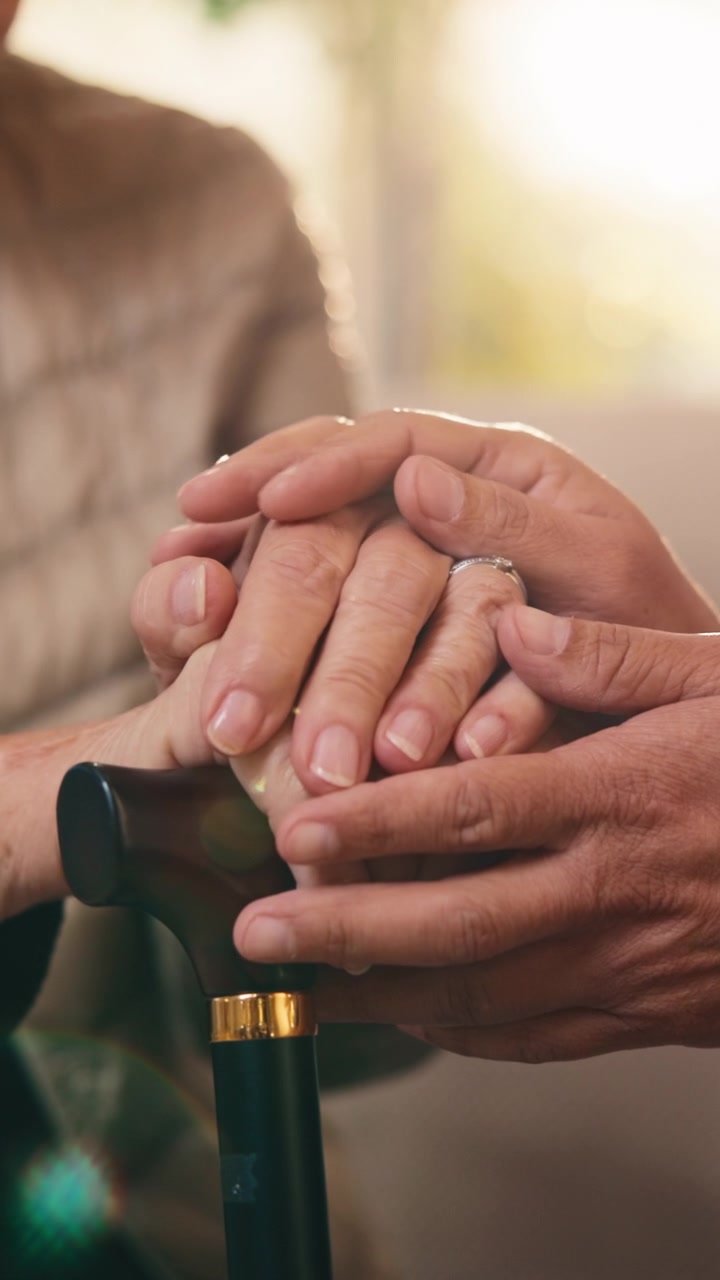 Primer plano de una persona consolando a una mujer mayor que sostiene un bastón
