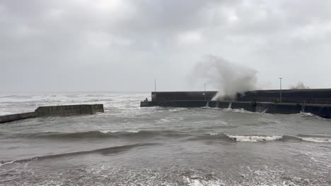 el paisaje marino gris: las olas de la tormenta chocan sobre el rompeolas de la marina en slo mo
