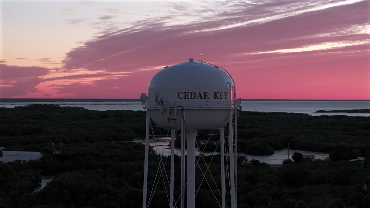 Iconic Cedar Key fishing village water tower standing tall against a breathtaking pink and gold sunrise on "Old Florida" Historic Nature Coast