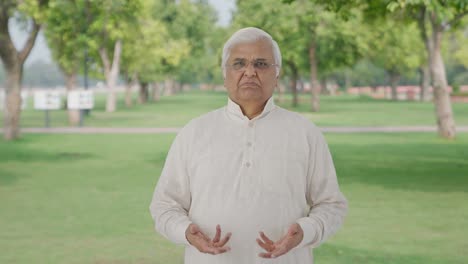 sad indian old man talking to someone in park