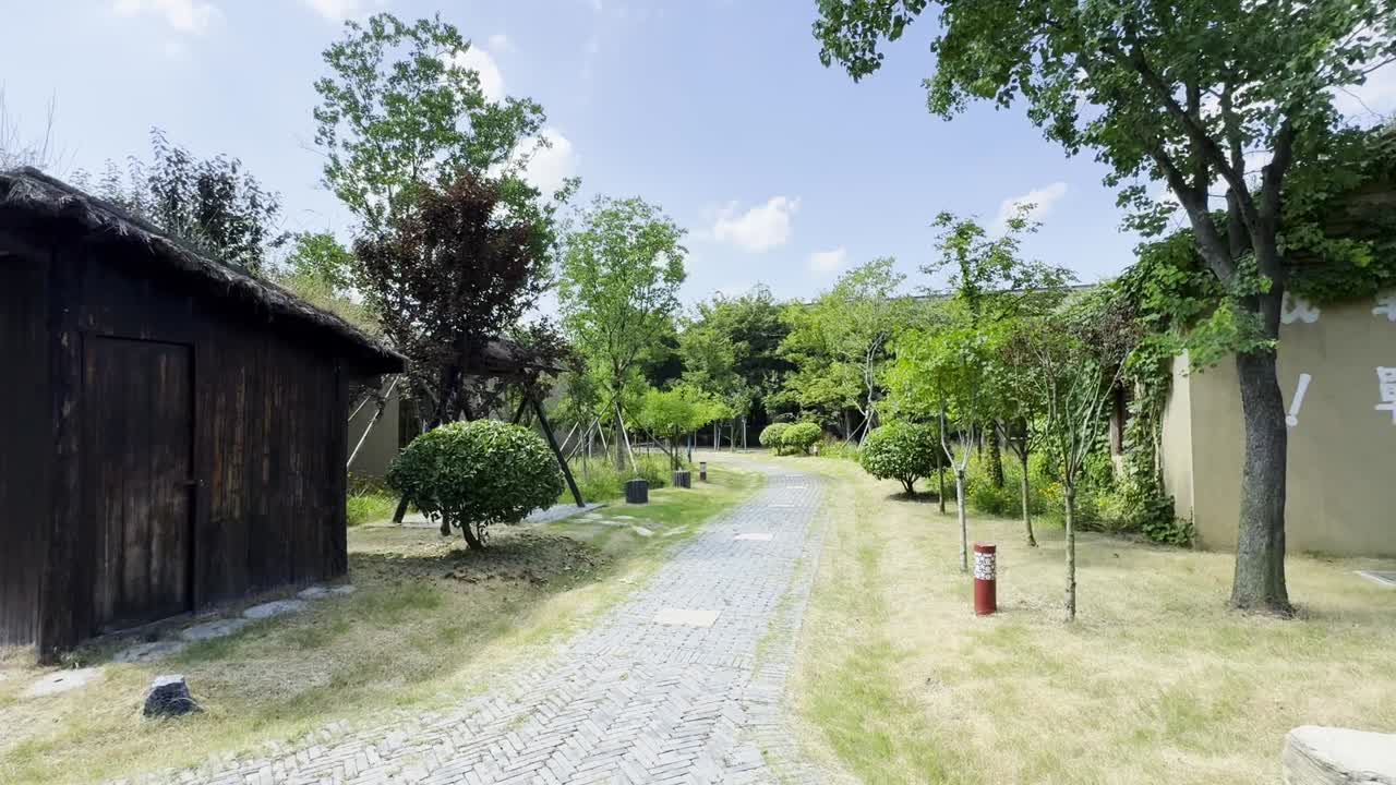 Old earth houses sit empty in a serene park in China, encircled by greenery