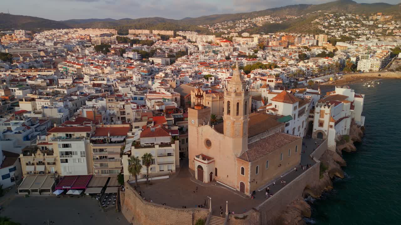 Luftfoto af kystbyen Sitges og kirken i den gyldne time.
