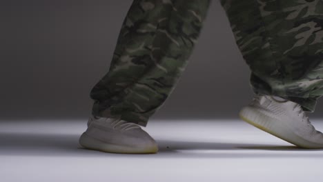 fotografía de estudio de cerca que muestra los pies de una mujer bailando con una iluminación de bajo tono contra un fondo gris