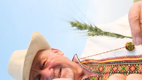 satisfied and happy grandfather in hat and embroidered shirt holding ear of corn and looking at satisfied and happy grandfather in hat and embroidered shirt holding ear of corn and looking at camera happy people