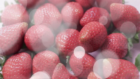 composition of spots of light over strawberries on pink background