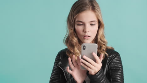 teenage caucasian girl in leather jacket using her smartphone.