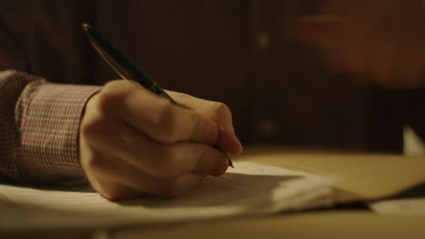 person writing and using a calculator at a desk