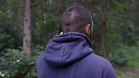 man in a hoodie walking in the woods