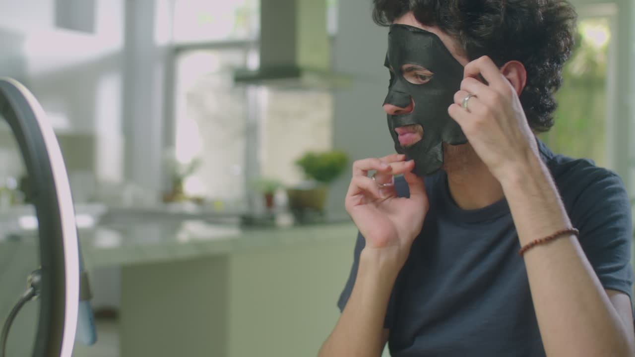 Male Beauty Blogger Applying Sheet Mask to Face