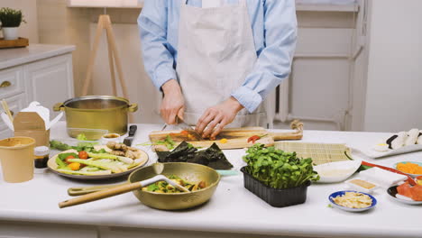 japanese man cutting ingredients in the kitchen, then looks at the camera and smiles 2