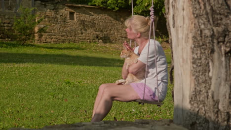 slide reveals woman and adorable ginger cat enjoying garden swing slow motion