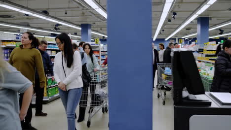people shopping and moving through supermarket aisles with carts