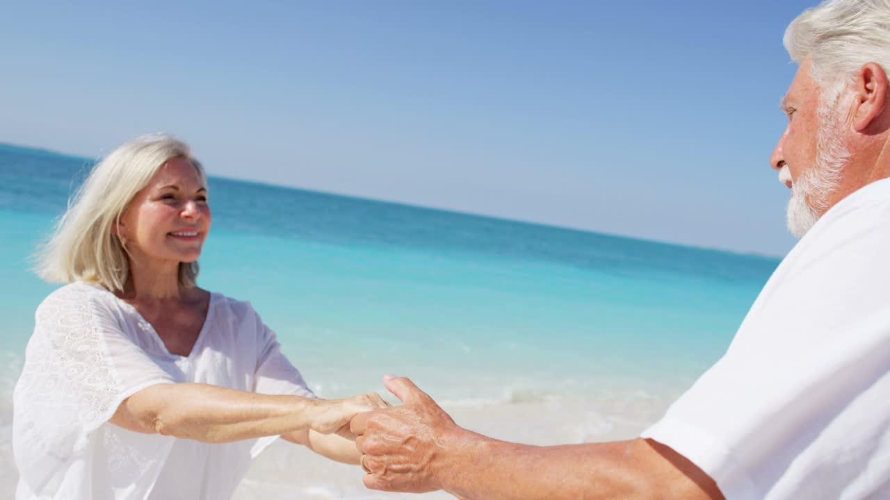 una pareja caucásica senior bailando compartiendo un beso en la playa.