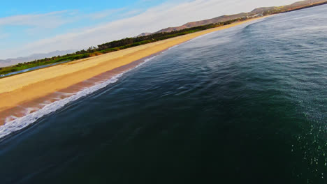 fpv drone shot over the ocean along the beautiful beach in baja region of mexico