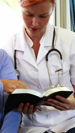 senior woman and nurse reading a book together