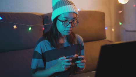 very concentrated asian woman playing video games on a laptop