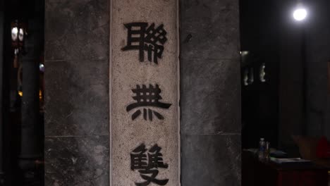 close-up of carved chinese characters on a stone pillar at night