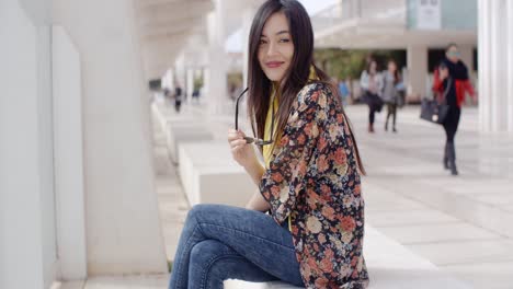 Thoughtful-young-woman-sitting-on-a-promenade