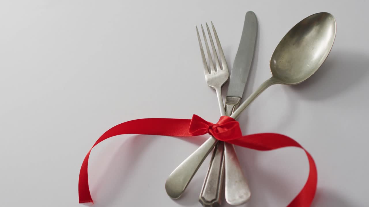 Cutlery and red ribbon on pink background at valentine's day