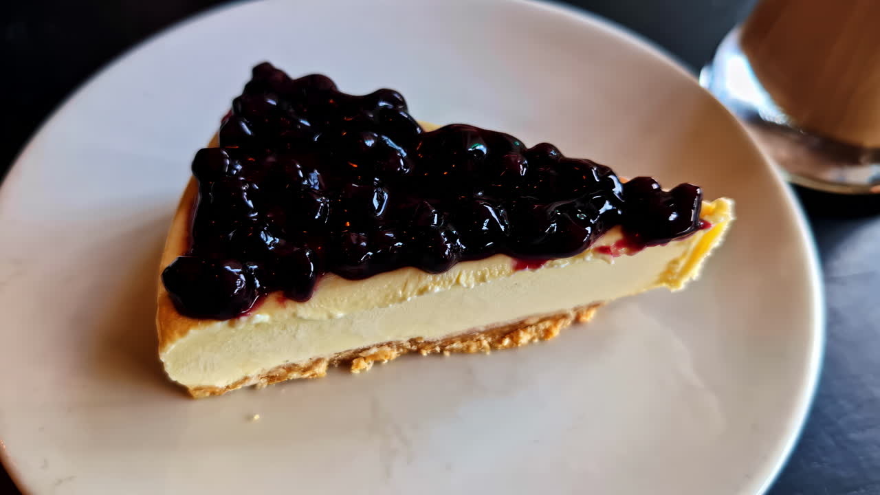 Slice of blueberry cheesecake on plate with coffee, cozy dessert moment indoors