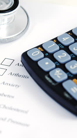 close-up of health evaluation form with diabetes check and calculator, stethoscope