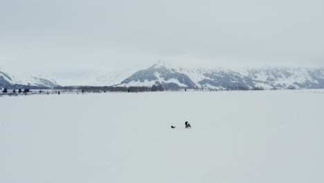 孤獨的冒險家站在開放的白色雪地風景旁邊的滑雪車,空中