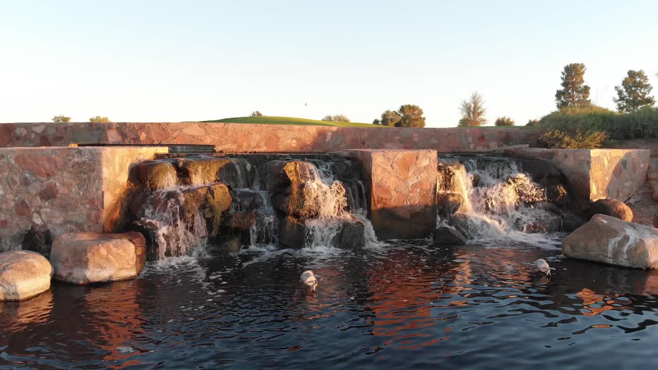 Drone footage from a golf course near a residential neighborhood in Arizona. Close up shot of the feature in a water hazard