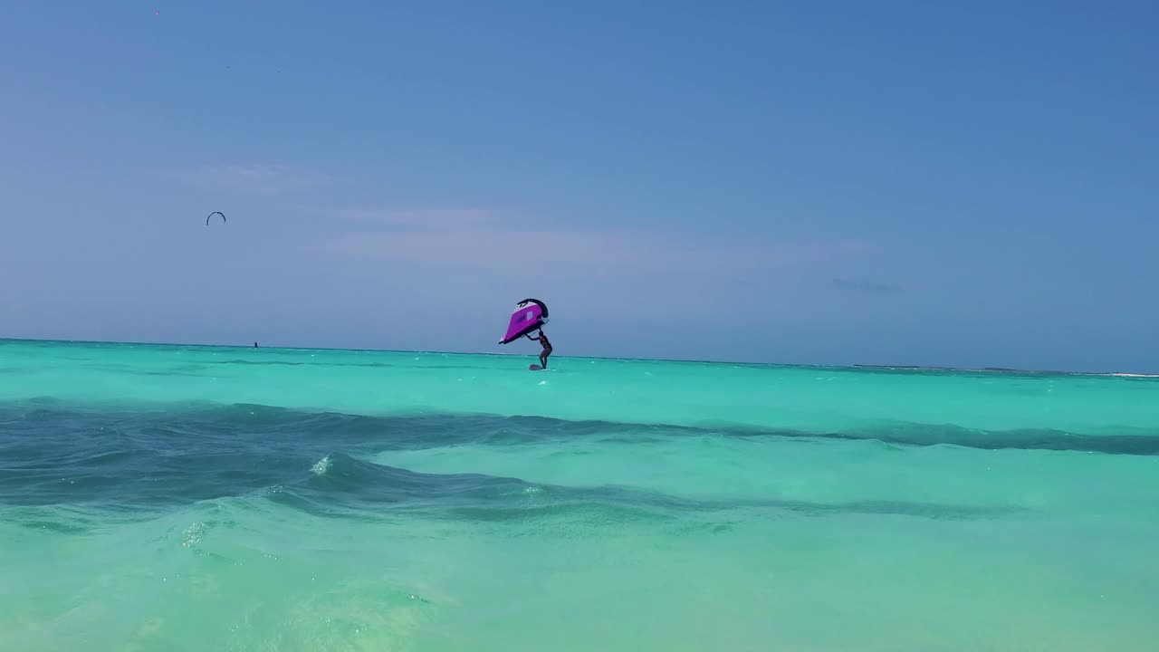 여성의 실루 ⁇ 은 바람을 따라 날기 시작합니다. 날개 포일 카이트, 푸른 카리브 해에서 극단적인 스포츠