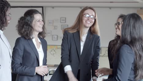 mujeres de negocios sonrientes estrechando la mano en la oficina