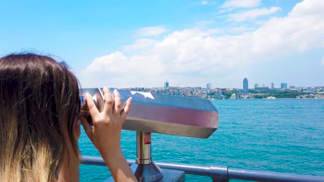 slow motion:beautiful girl looks through sightseeing binoculars on bosphorus,a popular destination in uskudar,istanbul,turkey