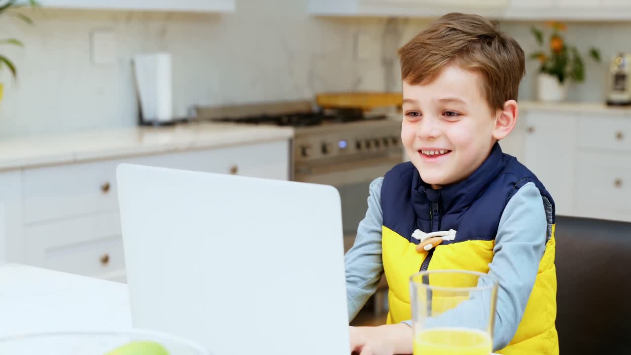 chico usando computadora portátil en la cocina 4k