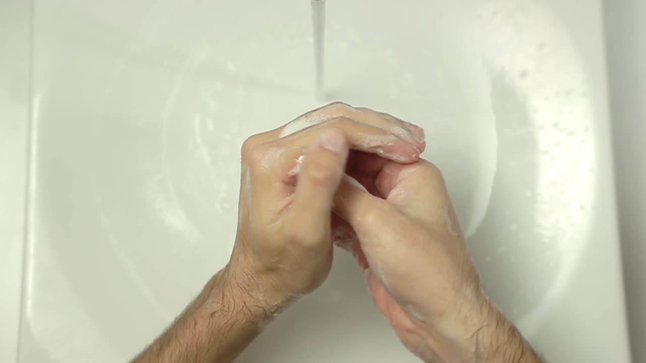 Top View of Person Washing Hands with Soap and Water in Sink
