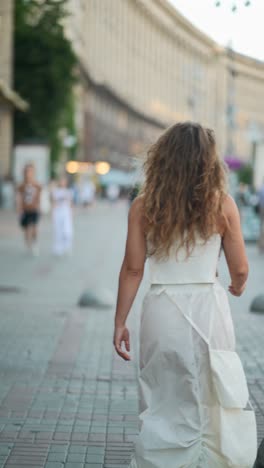 woman in white dress walking down city street