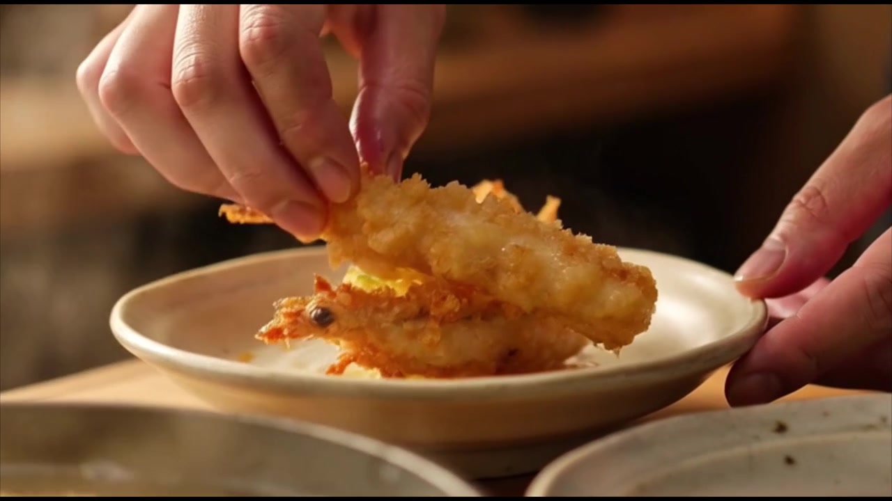 Chef che posiziona tempura di gamberi appena fritta su un piatto
