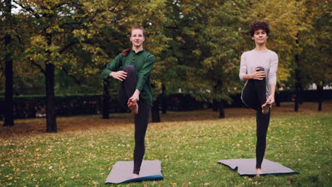 two women practicing yoga outdoors in autumn